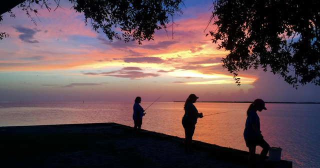 Family fishing at sunset at Cypremort Point State Park in Louisiana