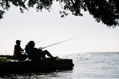 Men sitting and fishing on the edge of the water - Photo by Louisiana Travel