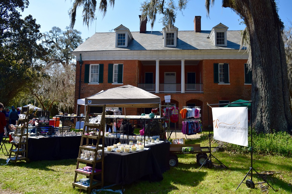 Several booths on the lawn at the Shadows arts and crafts fair with Shadows-on-the-Teche plantation home in the background