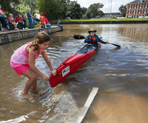 A girl pulls a paddler's canoe to the New Iberia City Park boat dock